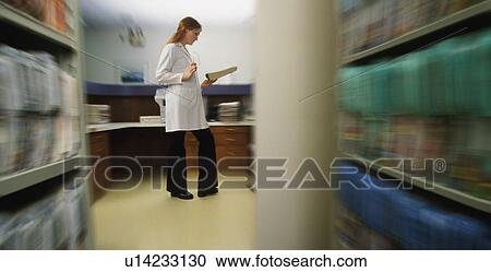 Stock Image - Doctor or nurse reading patient record. Fotosearch