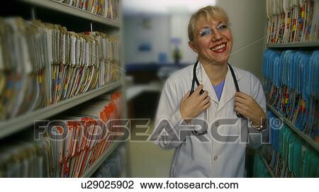 Stock Image - Doctor standing beside patient records. Fotosearch