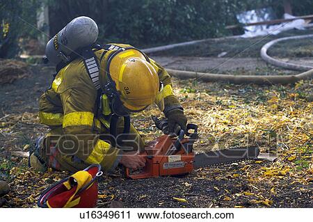 Stock Image - Fireman starting chainsaw. Fotosearch
