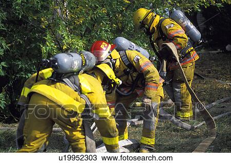 Firemen outside picking up fire hose View Large Photo Image Stock Image - Firemen outside picking up fire hose. Fotosearch