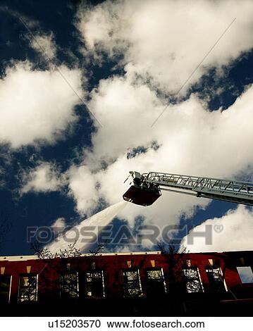 Firemen spraying water from ladder above building View Large Photo Image Stock Image - Firemen spraying water from ladder above building. Fotosearch