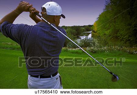 Stock Image - Follow through of golfer's tee shot. Fotosearch