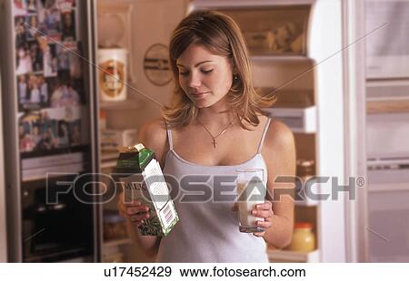 Stock Photo - Girl getting glass of milk from fridge. Fotosearch