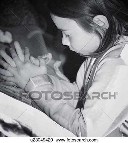 Stock Image - Girl kneeling and praying by bed. Fotosearch