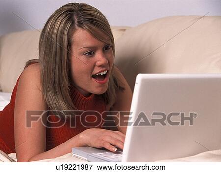 Stock Photo - Girl laying on sofa with laptop computer. Fotosearch