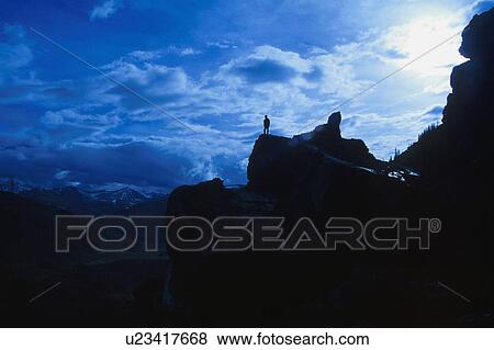 Hiker standing on large rock at edge of cliff View Large Photo Image Stock Photo - Hiker standing on large rock at edge of cliff. Fotosearch