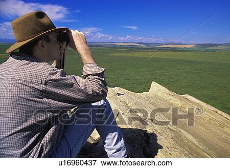 Stock Photo - Hiker with binoculars on cliff edge. Fotosearch