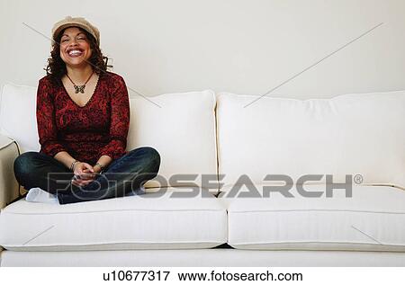 Stock Photo - Laughing woman sits on sofa. Fotosearch