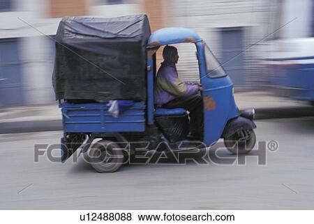 ma driving a three-wheeled van View Large Photo Image Stock Photo - ma driving a three-wheeled van. Fotosearch