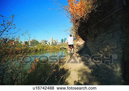 Man cycling on path beside river View Large Photo Image Stock Photo - Man cycling on path beside river. Fotosearch