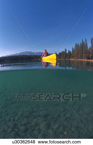 Stock Photo - Man in yellow canoe on lake. Fotosearch