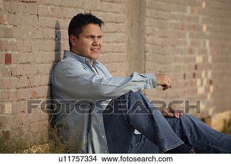 Picture - Man leans against wall. Fotosearch