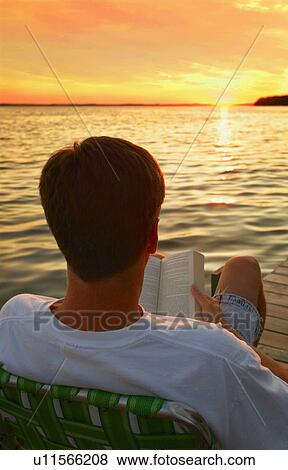 Stock Photo - Man reading a book at the lake. Fotosearch