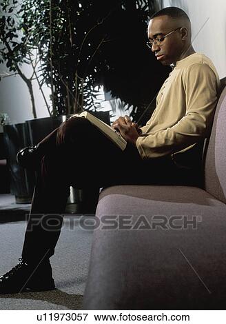 Stock Photo - Man reading on couch. Fotosearch