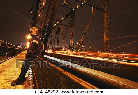 Man sits on side of bridge View Large Photo Image Stock Image - Man sits on side of bridge. Fotosearch