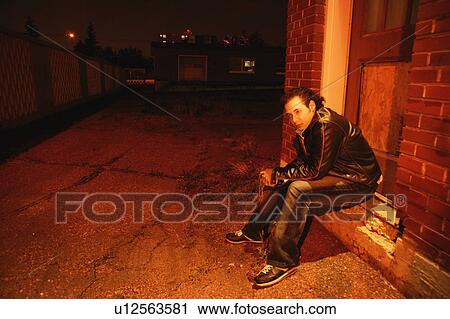 Stock Image - Man sits under street light. Fotosearch