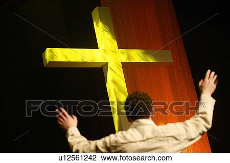 Stock Image - Man standing at cross worshipping. Fotosearch