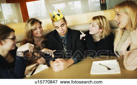 Stock Photo - Man with flimsy crown on head and women paying attention to him. Fotosearch