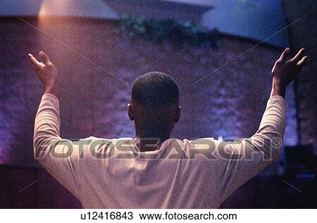 Stock Image - Man with hands raised in worship. Fotosearch