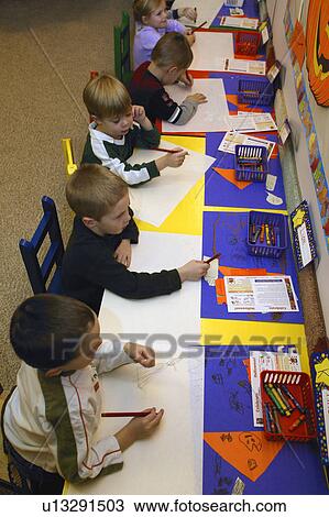 Stock Image - Many children drawing and having fun together in their kindergarten class. Fotosearch