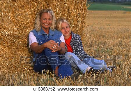 Stock Image - Mom and daughter resting in the hayfield. Fotosearch