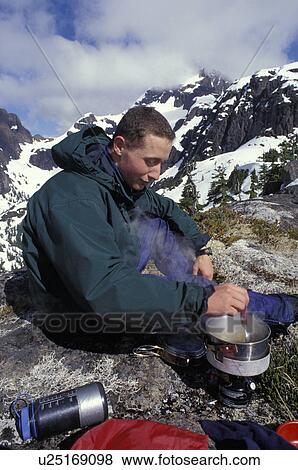 Stock Photo - Mountaineer using a camping stove. Fotosearch