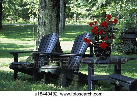 Stock Image - Outdoor chairs and table with red pot plant. Fotosearch