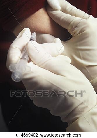 Stock Image - Patient receiving injection in arm. Fotosearch