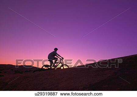 Stock Photo - Person on bike at sunset. Fotosearch