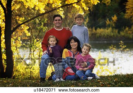 Stock Image - Portrait of family in park by river. Fotosearch