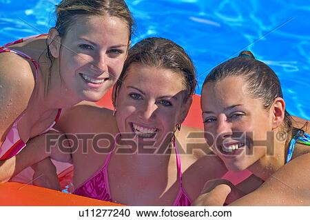 Stock Image - Portrait of three young women in swimming pool. Fotosearch
