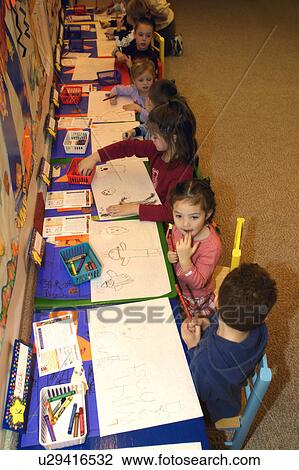 Stock Image - Preschool age children drawing pictures in their kindergarten class. Fotosearch