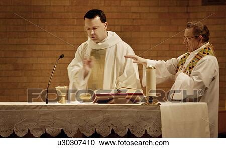 Stock Image - Priests praying over communion. Fotosearch