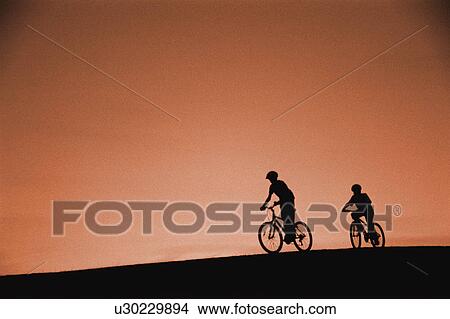 Picture - Silhouette of cyclists on hill. Fotosearch