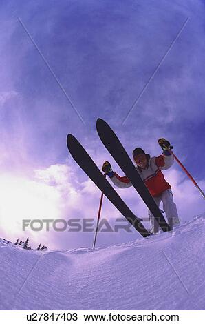 Stock Image - Skier on edge of slope viewed from underneath. Fotosearch
