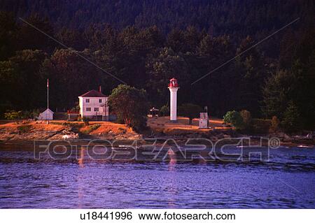 Stock Photograph - Small lighthouse with trees and hill behind. Fotosearch