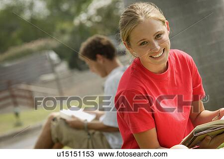 Stock Image - Smiling student reading outside. Fotosearch