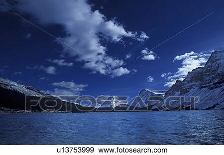 Snow-covered mountains across lake View Large Photo Image Stock Photo - Snow-covered mountains across lake. Fotosearch