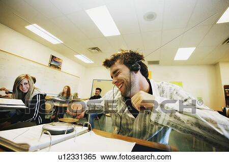 Stock Photography - Student listening to music at desk. Fotosearch