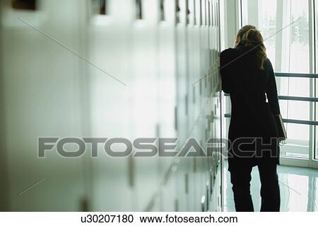 Stock Image - Student peers down hallway. Fotosearch