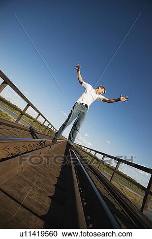 Stock Image - Teen walks on train tracks. Fotosearch