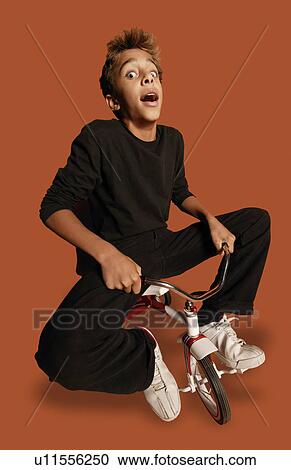 Stock Image - Teenage boy on tiny bicycle. Fotosearch
