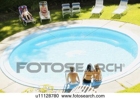 Stock Image - Teens sitting at a pool. Fotosearch