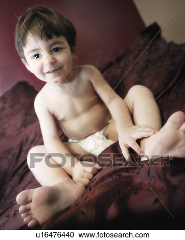 Stock Image - Toddler sitting on bed. Fotosearch