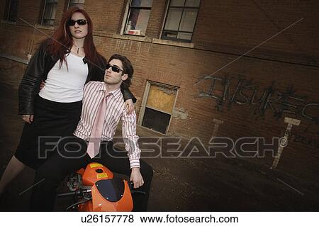 Trendy couple posing on a scooter View Large Photo Image Stock Photo - Trendy couple posing on a scooter. Fotosearch