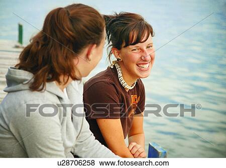 Stock Photo - Two girls sitting on a pier. Fotosearch