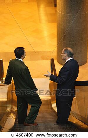 Two men have a conversation on an escalator View Large Photo Image Stock Image - Two men have a conversation on an escalator. Fotosearch