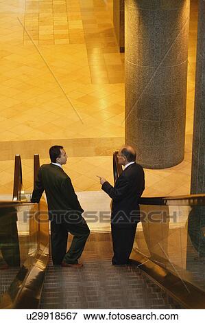 Stock Photo - Two men have a conversation on an escalator. Fotosearch