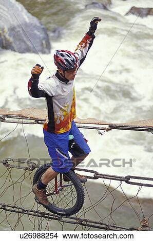 Unicyclist crossing river on unicycle View Large Photo Image Picture - Unicyclist crossing river on unicycle. Fotosearch