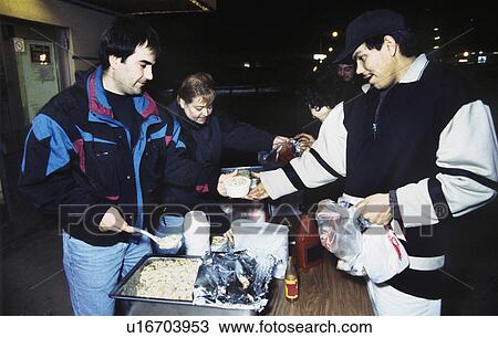 Stock Image - Volunteers and homeless at soup kitchen. Fotosearch